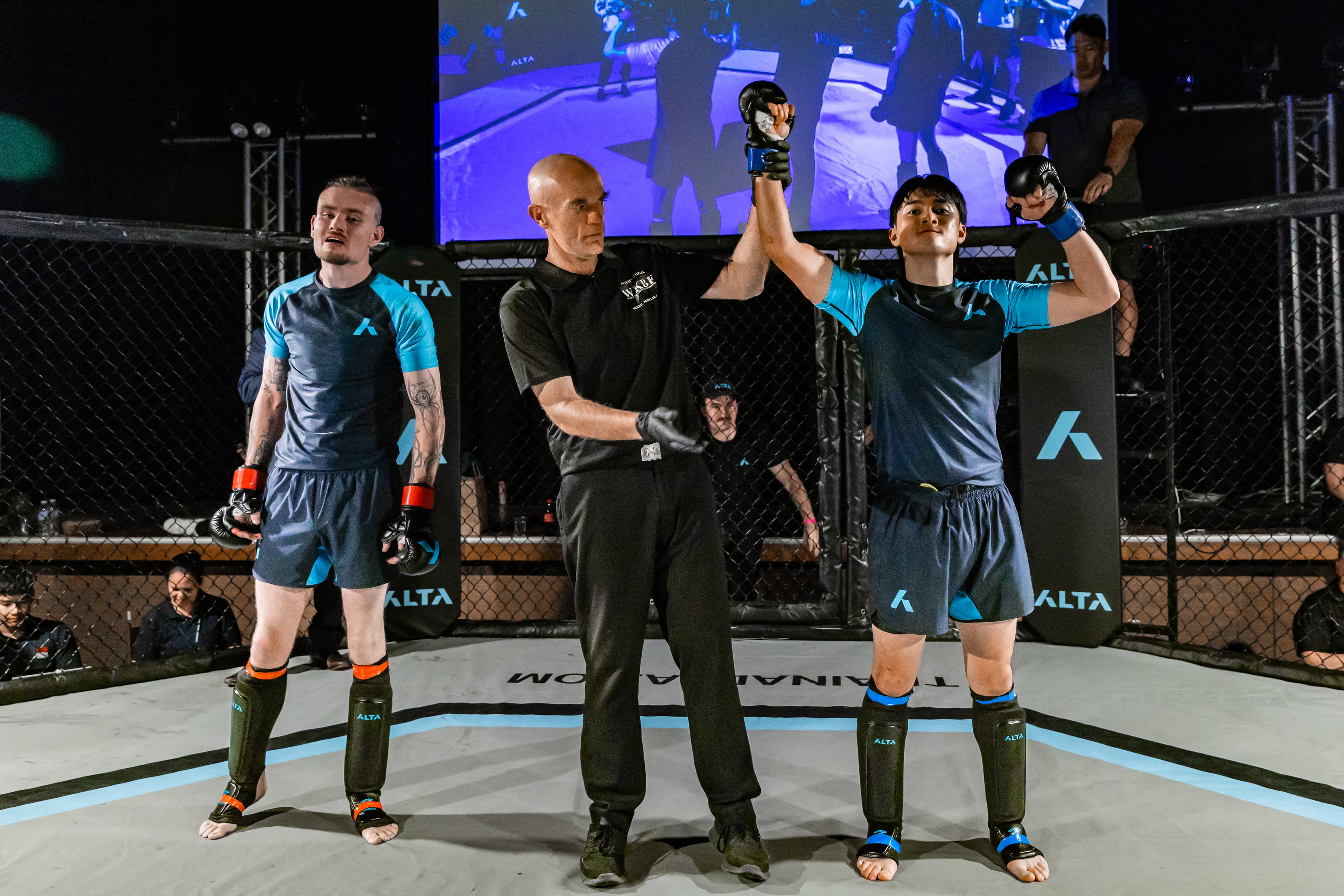 A referee raises the winning fighter’s hand at an Alta event